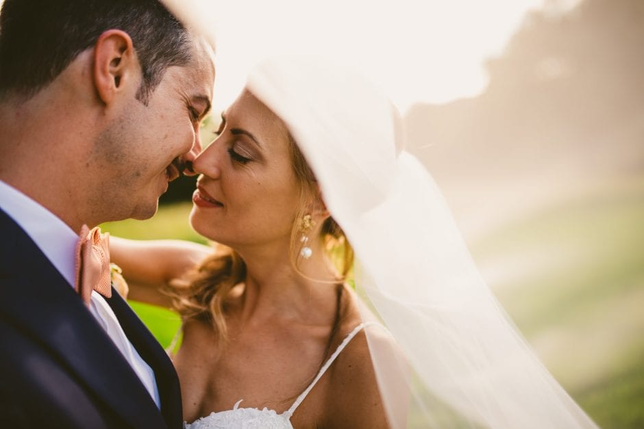 Gli sposi posano insieme con il velo della sposa che li avvolge dolcemente.