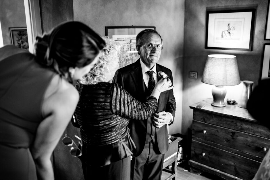La madre della sposa sistema la bottoniera al marito